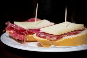 Close view of traditional Spanish tapas with salami and cheese on a plate.